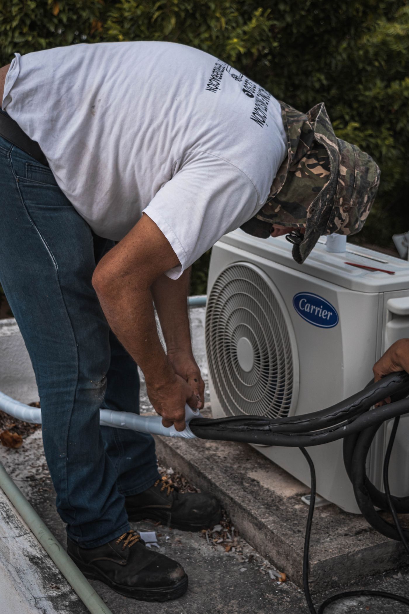Technician checking hose connections on an outdoor AC unit