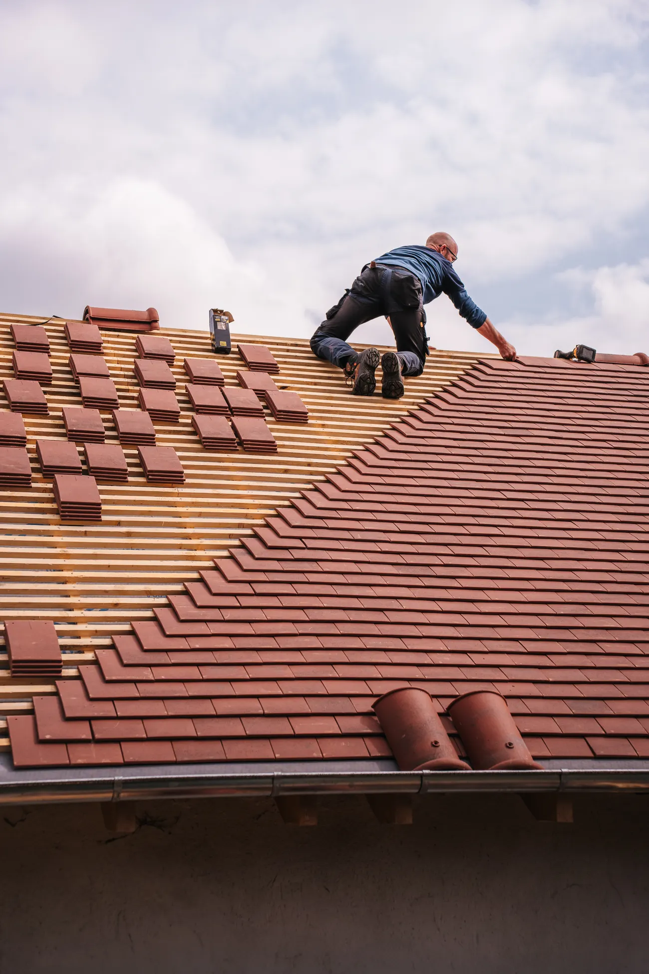 Roofer installing shingles on a new house roof